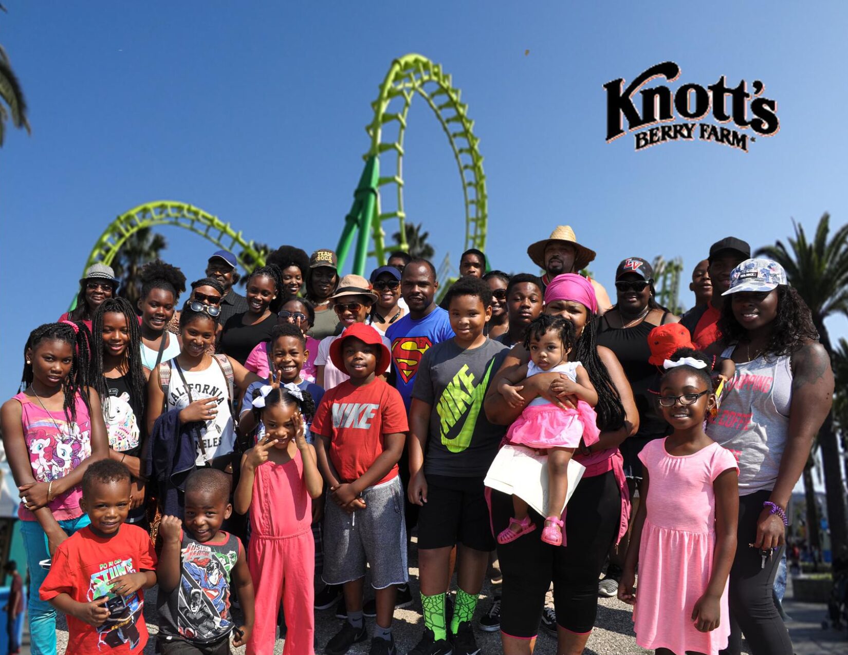 A group of people standing in front of a roller coaster.