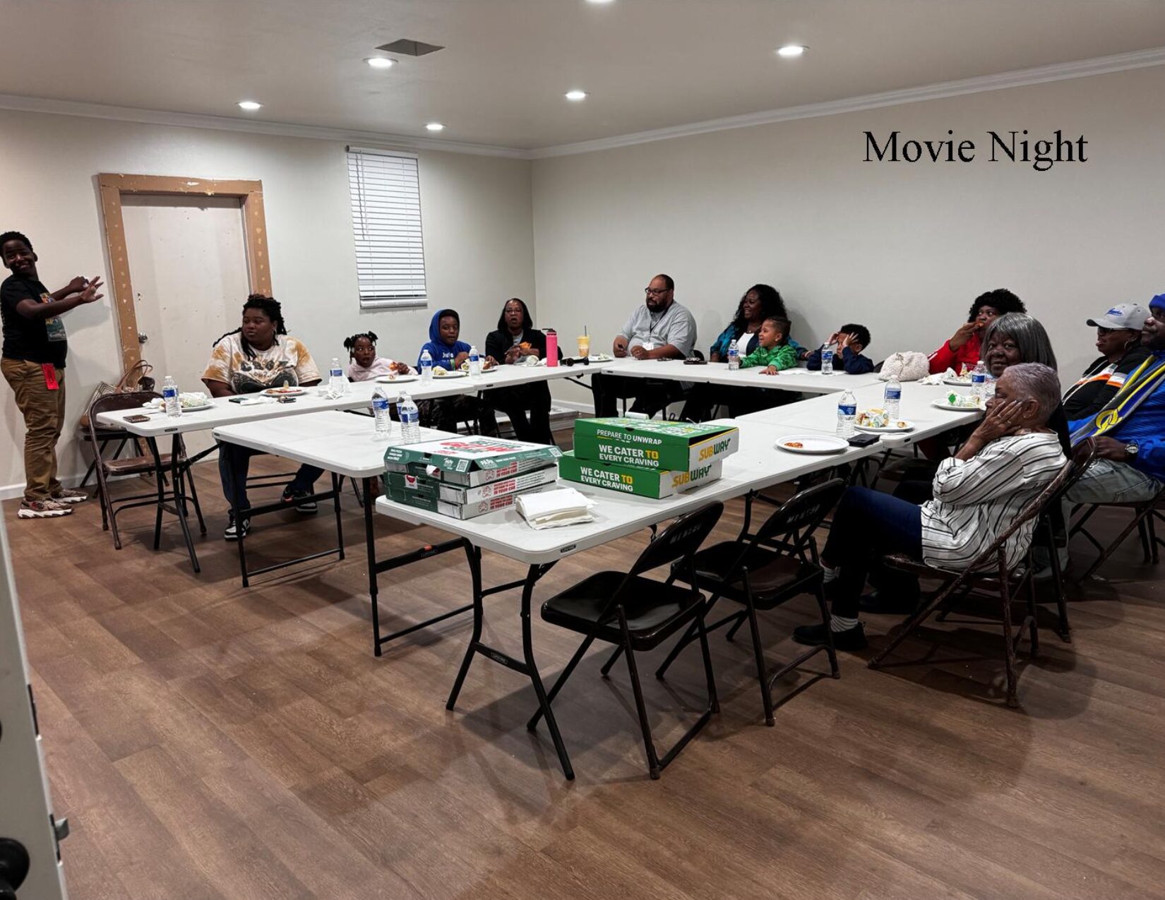 A group of people sitting at tables in front of boxes.