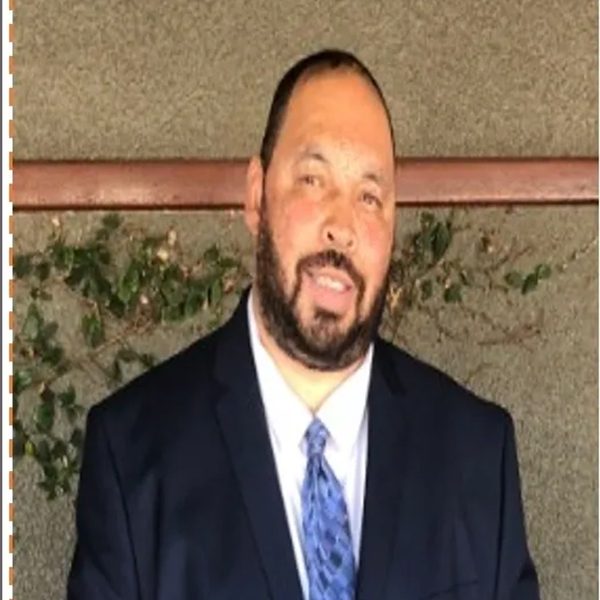 A man in a suit and tie standing next to a wall.