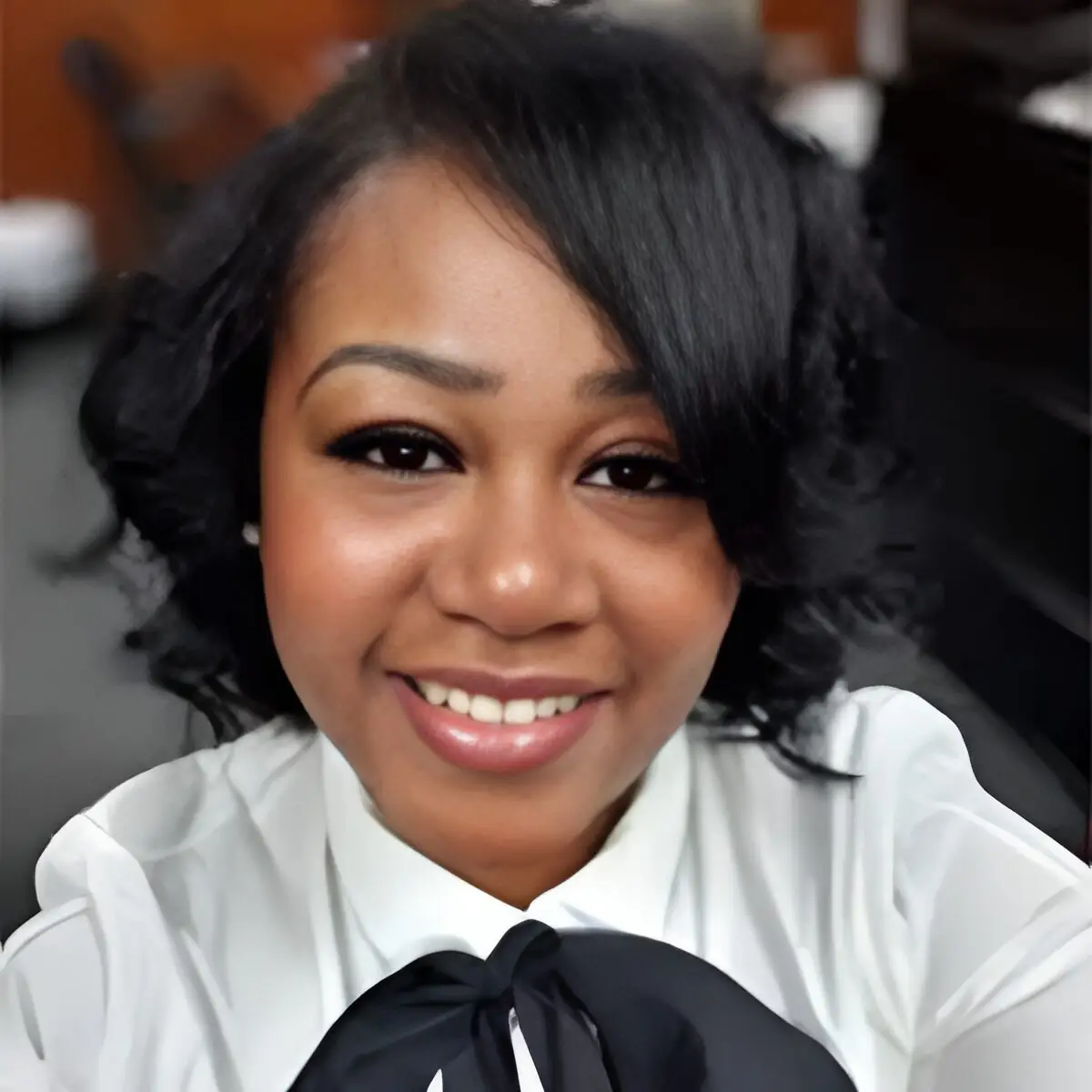 A woman with short hair wearing a white shirt and black tie.