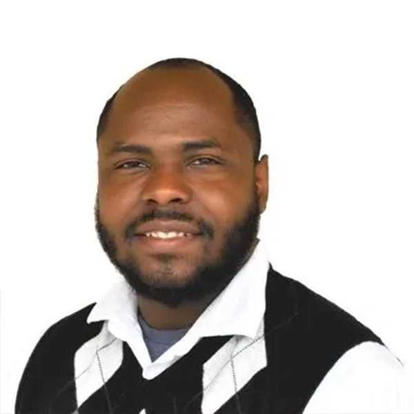 A man in black vest and white shirt smiling.