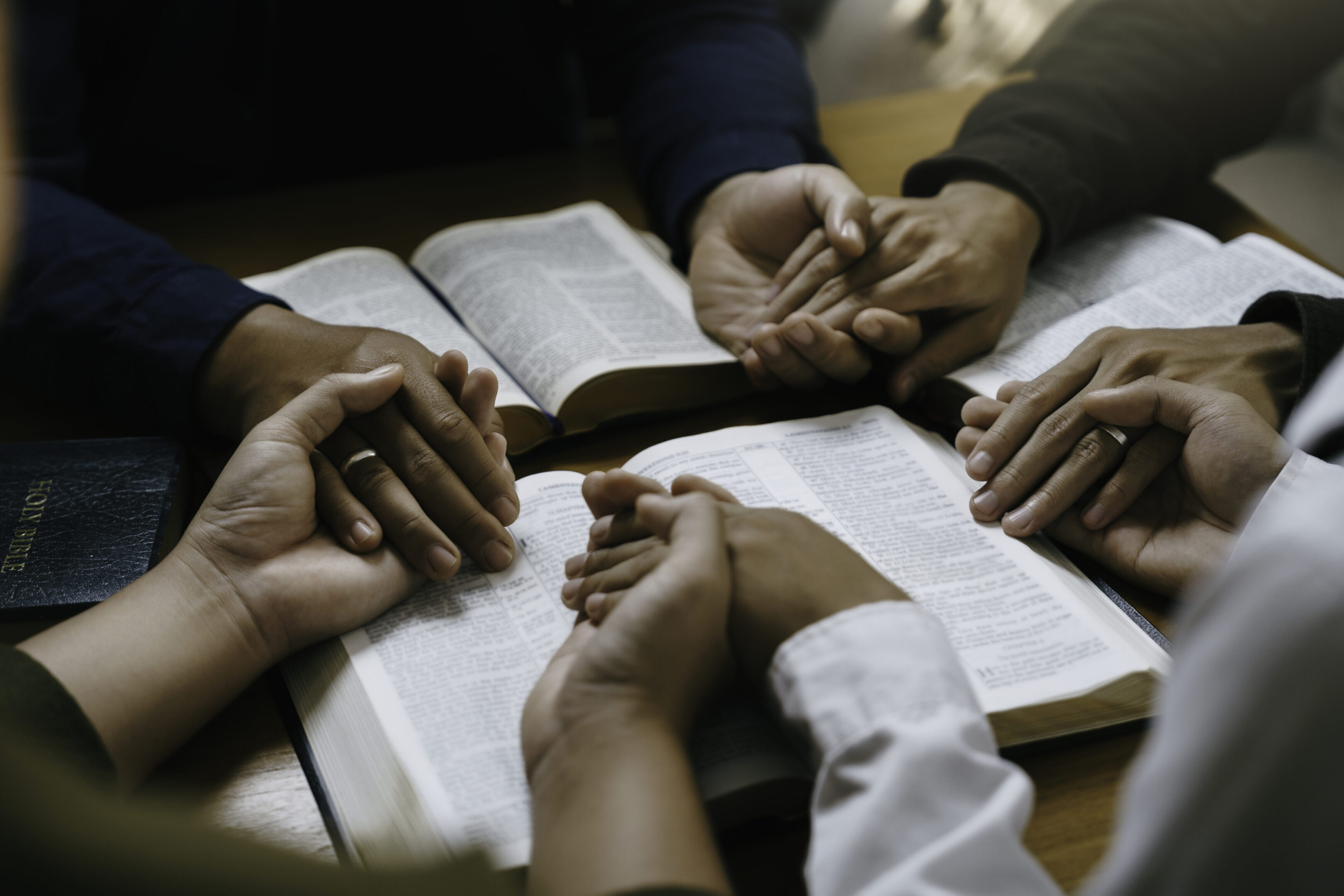 A group of people sitting around each other holding hands.